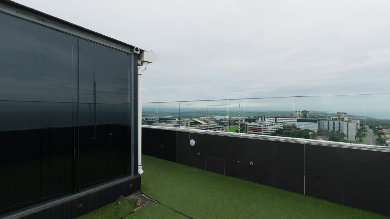 A rooftop terrace with a glass railing overlooking a city